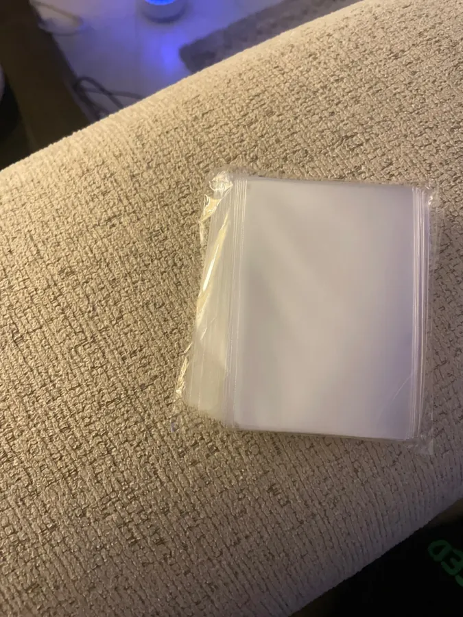 Buyer photo of a sealed penny sleeve pack on a sofa